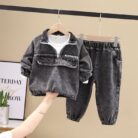 Stylish little boy smiling outdoors in a cool boys denim terno set.