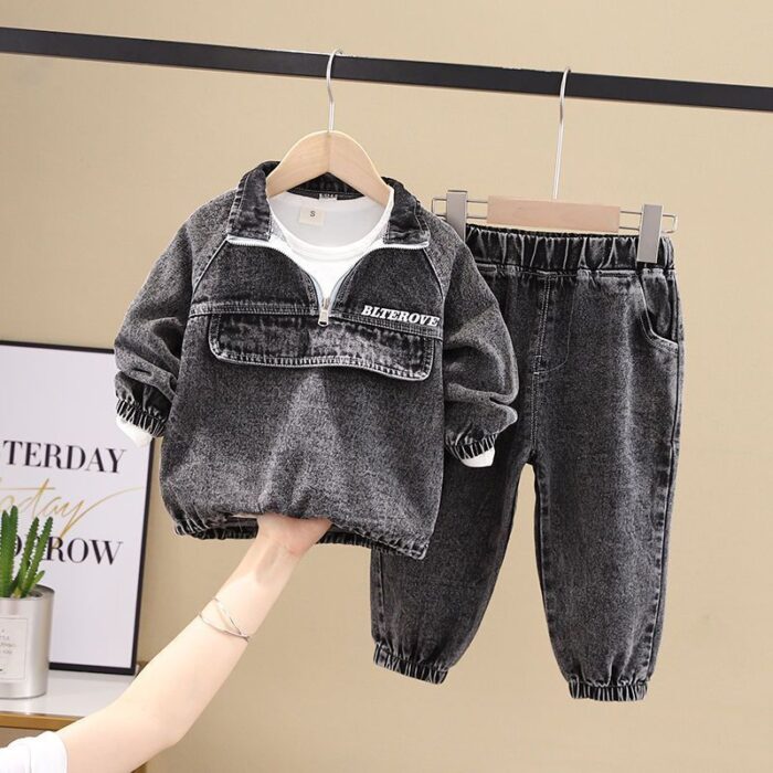 Stylish little boy smiling outdoors in a cool boys denim terno set.