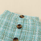Happy baby girl wearing a stylish baby girl plaid skirt set with a matching headband.