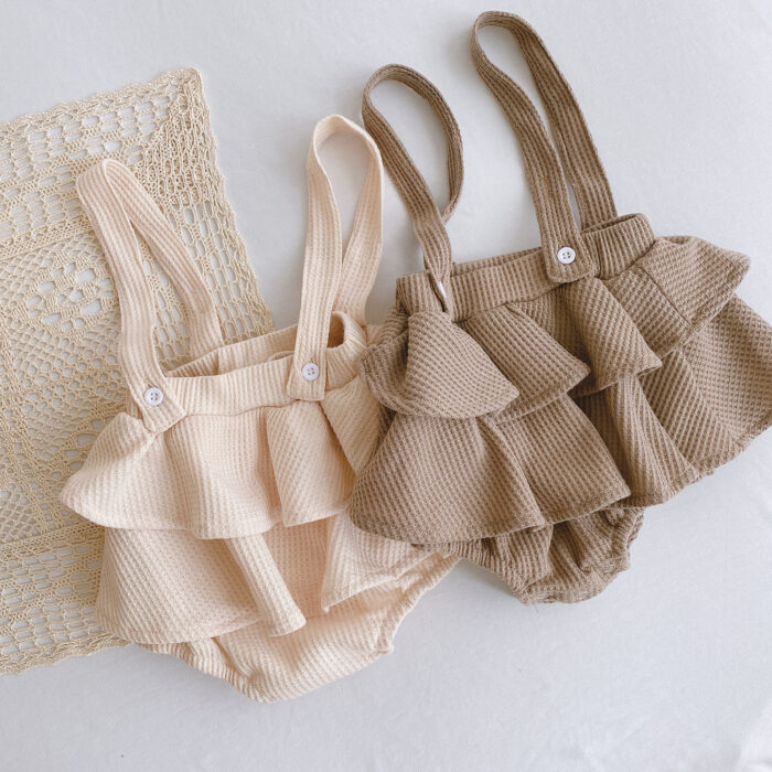 Adorable baby girl wearing a trendy boho baby girl suspender romper.