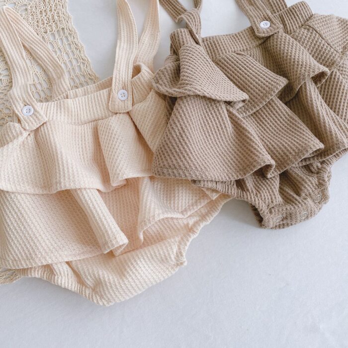 Adorable baby girl wearing a trendy boho baby girl suspender romper.