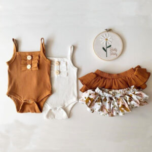 Baby girl smiling in a beautifully soft baby girl romper and skirt set.