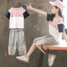 Older child smiling outdoors wearing a trendy pink kids sporty two piece set.