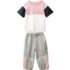 Older child smiling outdoors wearing a trendy pink kids sporty two piece set.