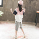 Older child smiling outdoors wearing a trendy pink kids sporty two piece set.