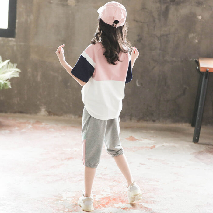 1623475056438.jpg Older child smiling outdoors wearing a trendy pink kids sporty two piece set.