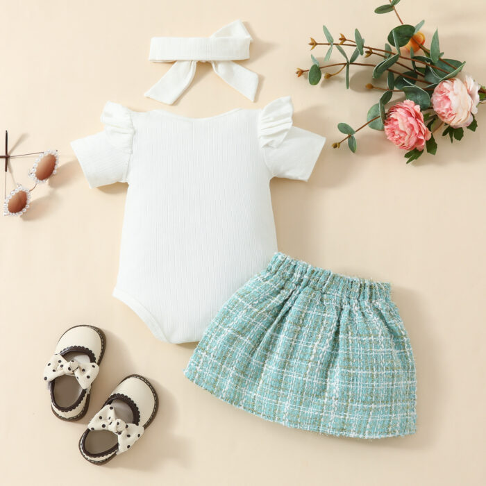Happy baby girl wearing a stylish baby girl plaid skirt set with a matching headband.