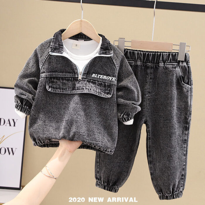 Stylish little boy smiling outdoors in a cool boys denim terno set.