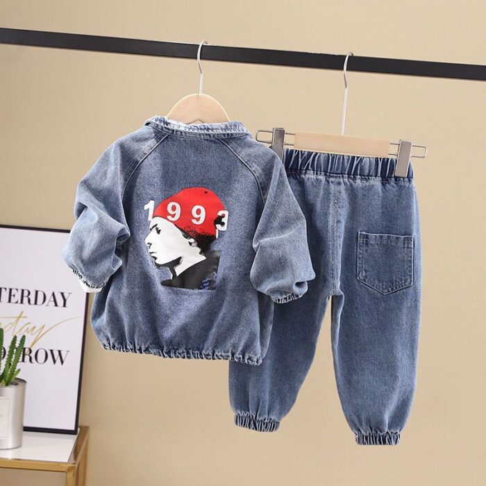 Stylish little boy smiling outdoors in a cool boys denim terno set.