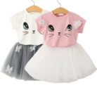 Young girl smiling and twirling in an adorable girls cat print skirt set.