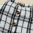 Happy baby girl wearing a stylish baby girl plaid skirt set with a matching headband.