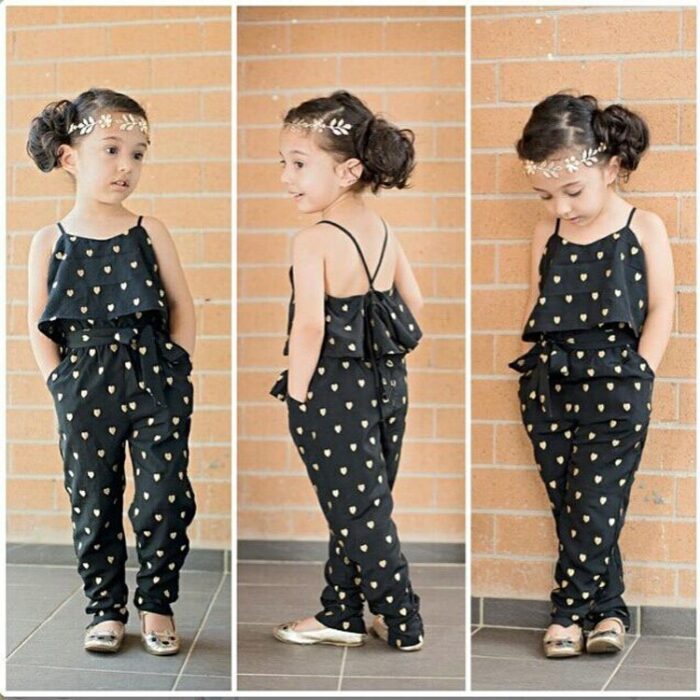 Young girl smiling outdoors wearing a stylish girls polka dot jumpsuit.