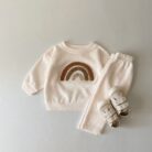 Cute baby wearing a neutral creamy-white baby embroidered two piece outfit.