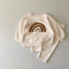 Cute baby wearing a neutral creamy-white baby embroidered two piece outfit.