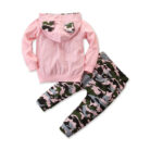 Stylish toddler girl smiling outdoors in a trendy pink toddler girl camo outfit.