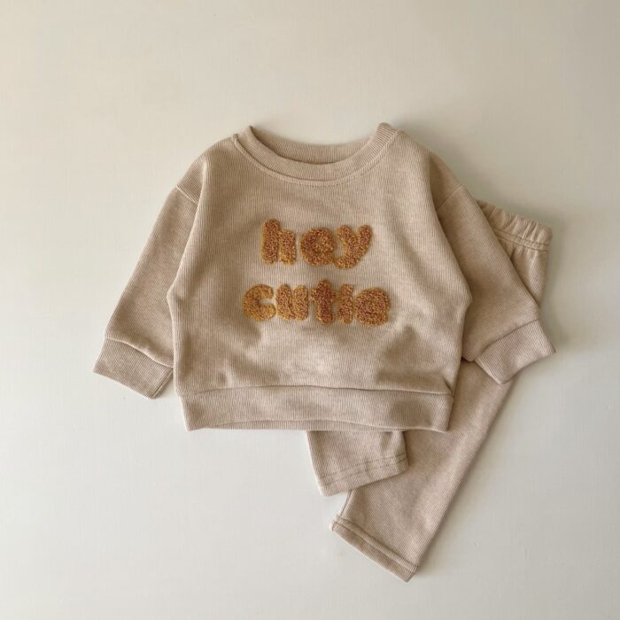 9f12efa7-cb1b-42c1-8a9e-940442fd6b8c.jpg Cute baby wearing a neutral creamy-white baby embroidered two piece outfit.