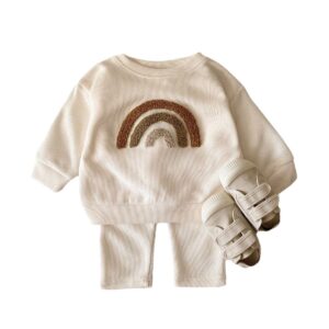 Cute baby wearing a neutral creamy-white baby embroidered two piece outfit.