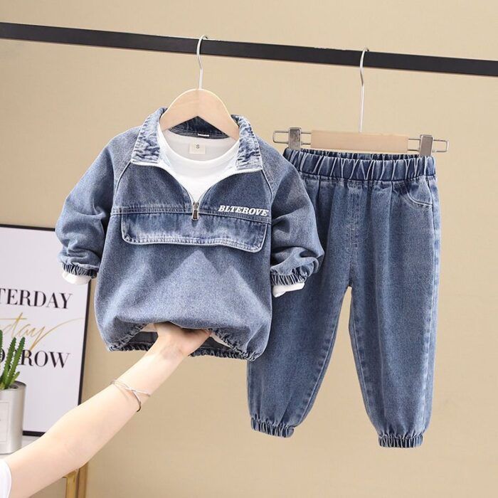 Stylish little boy smiling outdoors in a cool boys denim terno set.