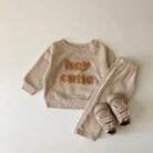 Cute baby wearing a neutral creamy-white baby embroidered two piece outfit.