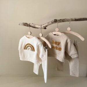 Cute baby wearing a neutral creamy-white baby embroidered two piece outfit.