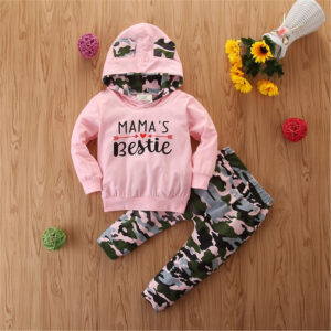 Stylish toddler girl smiling outdoors in a trendy pink toddler girl camo outfit.