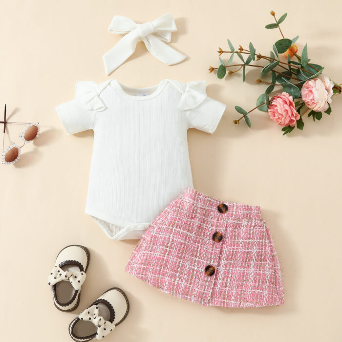 Happy baby girl wearing a stylish baby girl plaid skirt set with a matching headband.