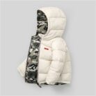 A happy little boy staying warm in the snow wearing a stylish boys reversible winter coat.