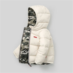A happy little boy staying warm in the snow wearing a stylish boys reversible winter coat.