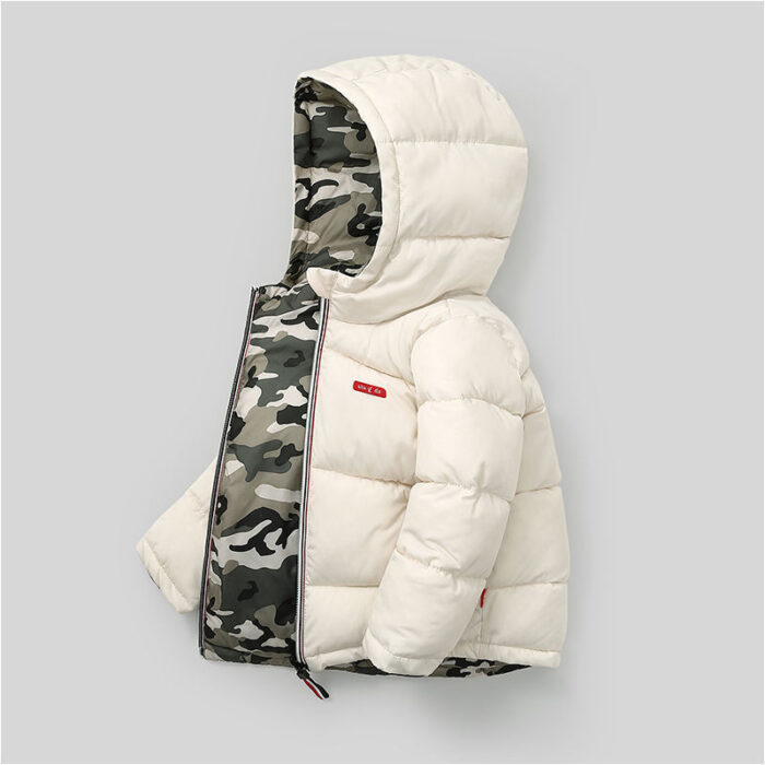 A happy little boy staying warm in the snow wearing a stylish boys reversible winter coat.