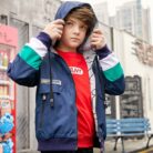 A young boy staying active outdoors wearing a vibrant boys hooded sports jacket.