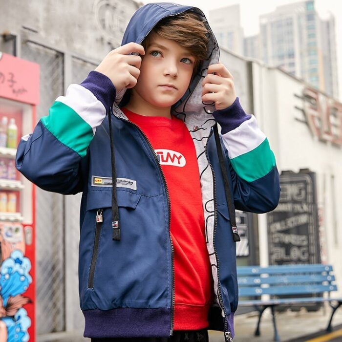 A young boy staying active outdoors wearing a vibrant boys hooded sports jacket.