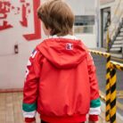 A young boy staying active outdoors wearing a vibrant boys hooded sports jacket.
