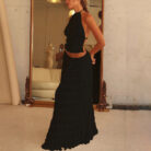 A woman wearing a stylish white two-piece halter crop top and pleated long maxi skirt set at the beach.