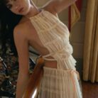 A woman wearing a stylish white two-piece halter crop top and pleated long maxi skirt set at the beach.